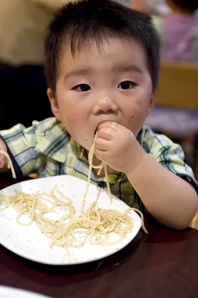 Eating baby to grab pasta with hand — Stock Photo, Image