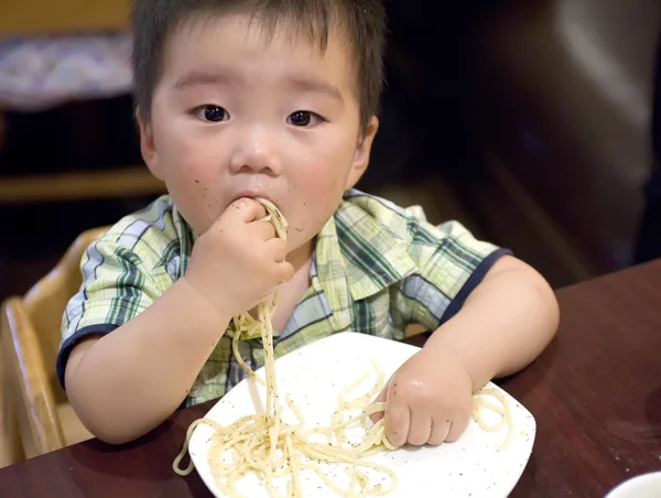 Jíst dítě chytit těstoviny s rukou — Stock fotografie