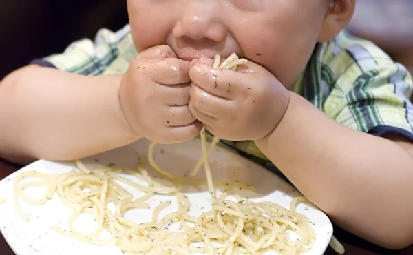 Mangiare bambino per afferrare la pasta con la mano — Foto Stock
