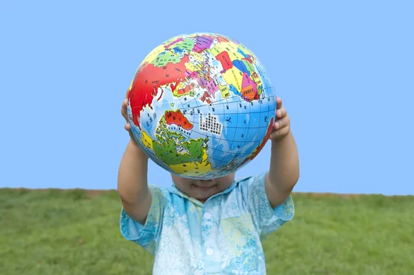 stock image Boy holding the earth model on the grass