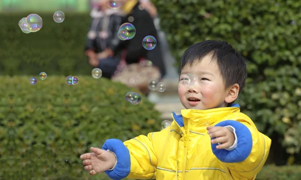 Bebê jogando bolhas de sabão — Fotografia de Stock