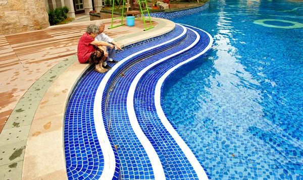 stock image An intimate senior couple sitting beside a pool