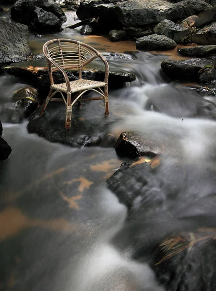 Lange blootstelling rotan leerstoel aan waterval. — Stockfoto