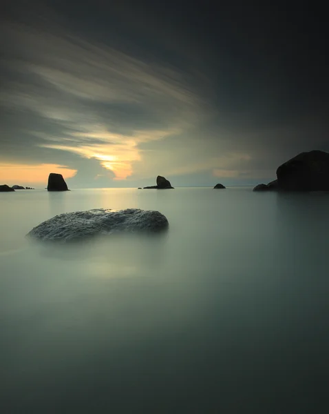 Prachtige lange blootstelling strand met rotsen bij zonsopgang. — Stockfoto
