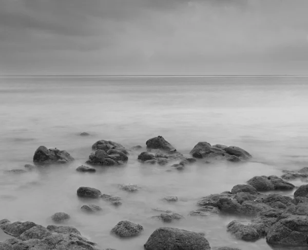 Fantastisk svart och vit lång exponering på stranden med stenar. — Stockfoto
