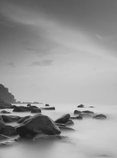 Plajda kayalar ile çarpıcı siyah-beyaz uzun pozlama. — Stok fotoğraf