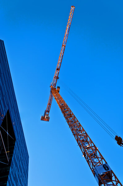 Skyscraper with tower crane on sky background
