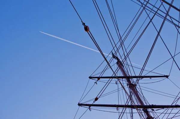 Schip mast met vliegtuigspoor op achtergrond — Stockfoto