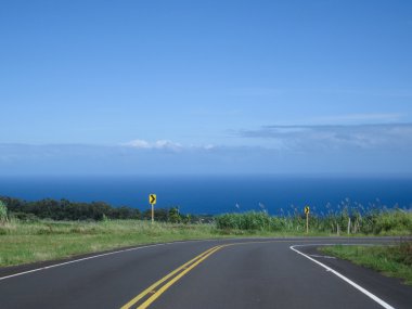 Road to the ocean with view of blue ocean and sky. clipart