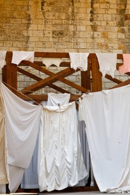 Sheets and clothes hung up to dry along an alley clipart