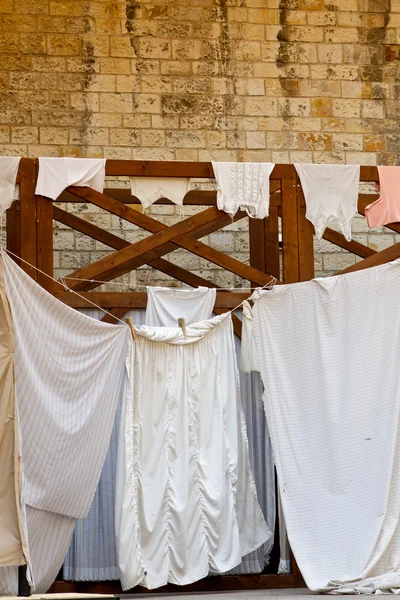Sheets and clothes hung up to dry along an alley