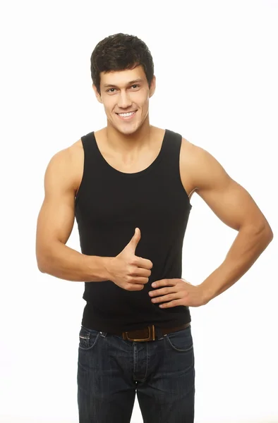 Exitoso joven musculoso mostrando el pulgar hacia arriba y sonriendo aislado en blanco — Foto de Stock