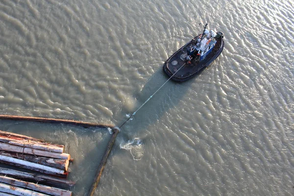 En bogserbåt drar en boom — Stockfoto