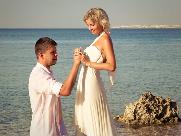 Bruidegom draagt ring bruid op strand — Stockfoto