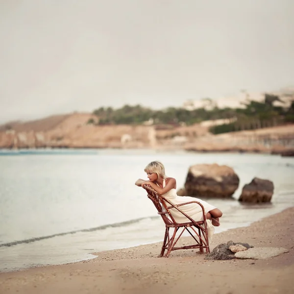 Mujer pensativa sentada en las dunas mirando el mar Imagen de archivo