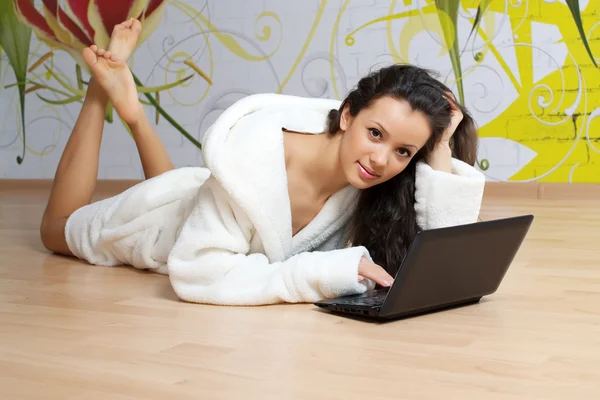 Giovane donna in vestaglia bianca con computer portatile — Foto Stock