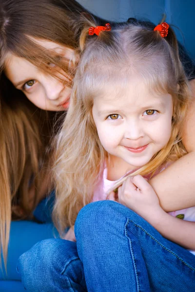 Δύο μικρά κορίτσια κάθονται αγκάλιασμα και χαμογελαστός — Φωτογραφία Αρχείου