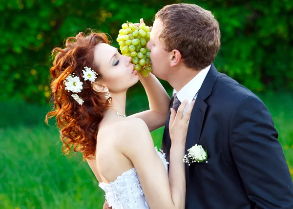 Nevěsta a ženich jíst zelené hrozny — Stock fotografie