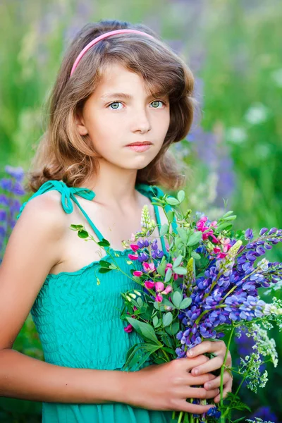 Holčička na poli s květinami — Stock fotografie