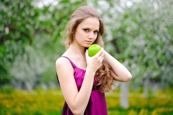 Hermosa chica con manzana, contra el verde jardín de verano — Foto de Stock