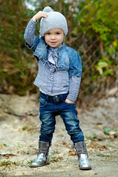 Красивая маленькая девочка в синих джинсах на открытом воздухе — стоковое фото