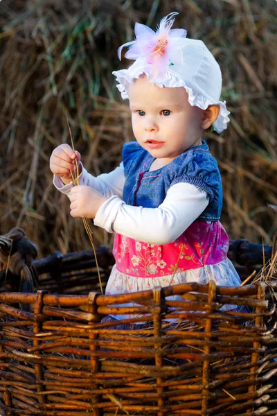 Kleines Mädchen posiert im Korb auf dem Heuboden — Stockfoto