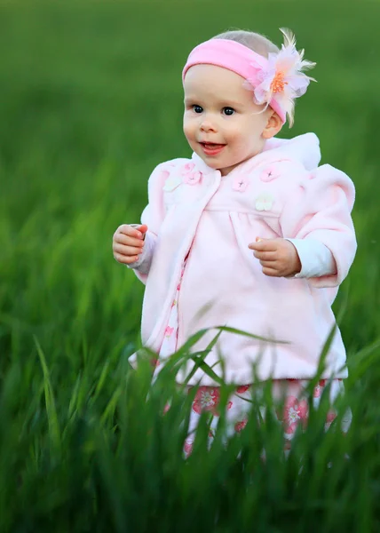 Маленькая девочка позирует в зеленой траве — стоковое фото