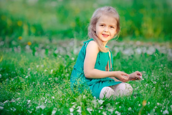 Blond liten flicka som leker i gräset — Stockfoto