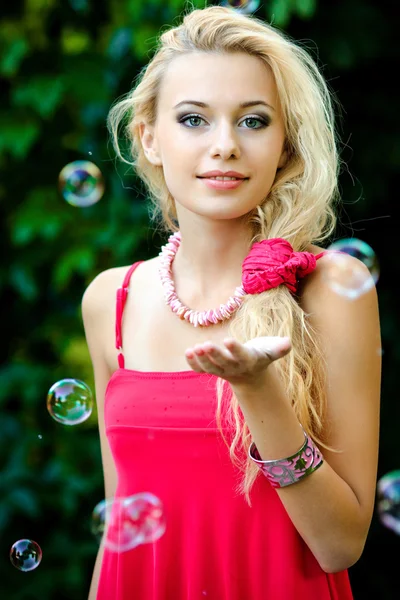 Bella ragazza bionda che gioca con bolle di sapone — Foto Stock