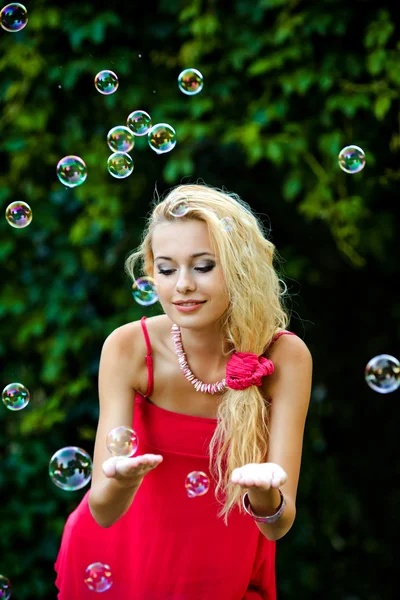 Beautiful blonde girl playing with soap bubbles — Stock Photo, Image