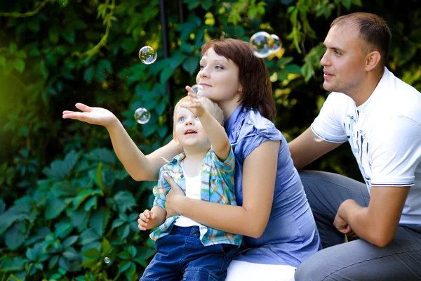 Famille heureuse jouant avec des bulles de savon — Photo
