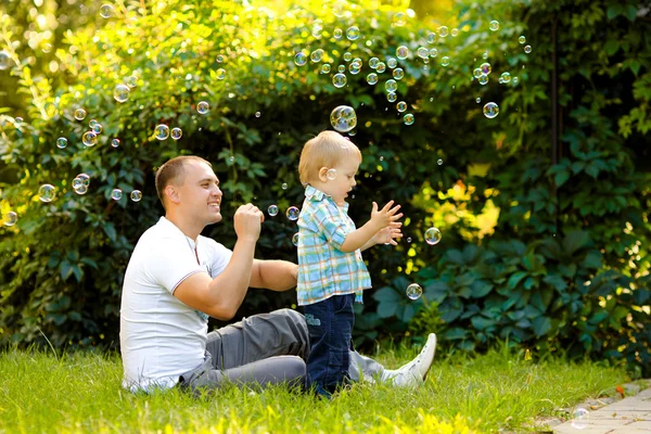 Отец и сын играют с мыльными пузырями — стоковое фото