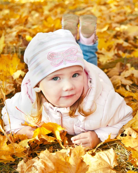 Μικρό κορίτσι ξαπλωμένο στο φύλλων το φθινόπωρο — Φωτογραφία Αρχείου