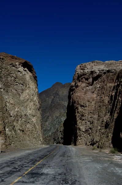 Road entering deep canyon with blue sky — Stok fotoğraf