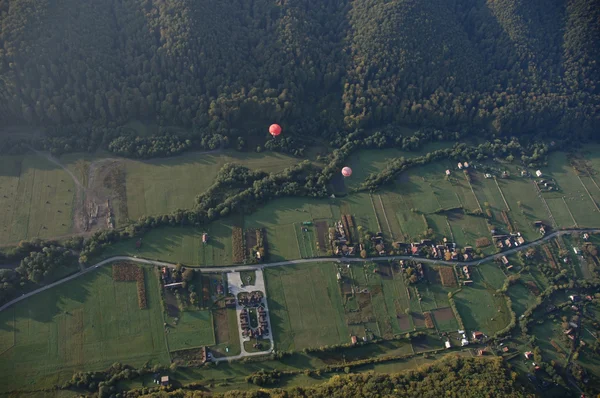 Luftaufnahme von Heißluftballons, die über dem Dorf fliegen — Stockfoto