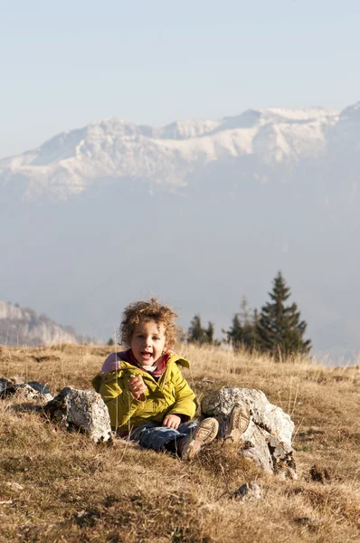 stock image Happy toddler girl on meadow with snow capped mountains background