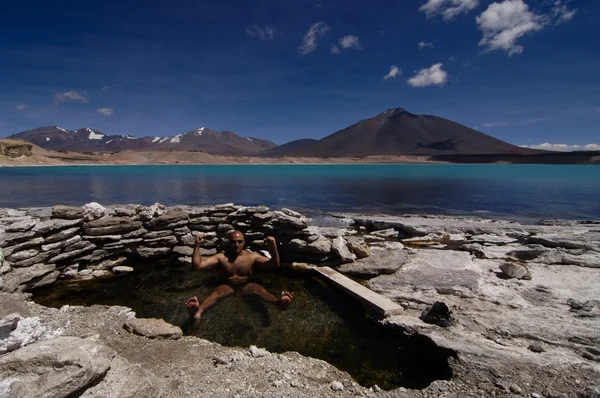 Человек отдыхает в горячих источниках у ледникового холодного озера — стоковое фото