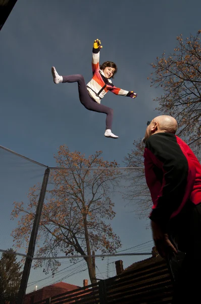 트램 폴 린에 지붕에서 점프 하는 어린 소녀 스톡 사진