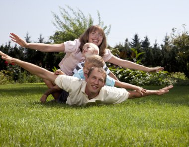 Family playing airplane on grass clipart