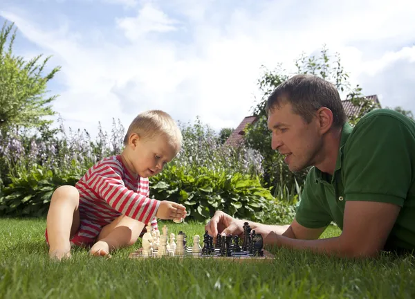 Kind und Vater spielen Schach im Garten — Stockfoto