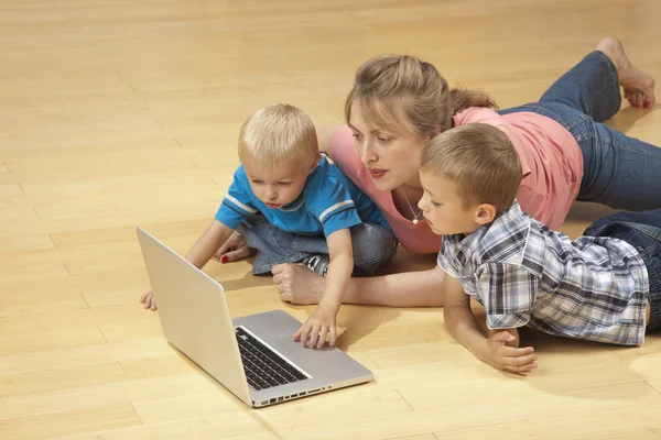 Familjen tittar på laptop på golvet — Stockfoto