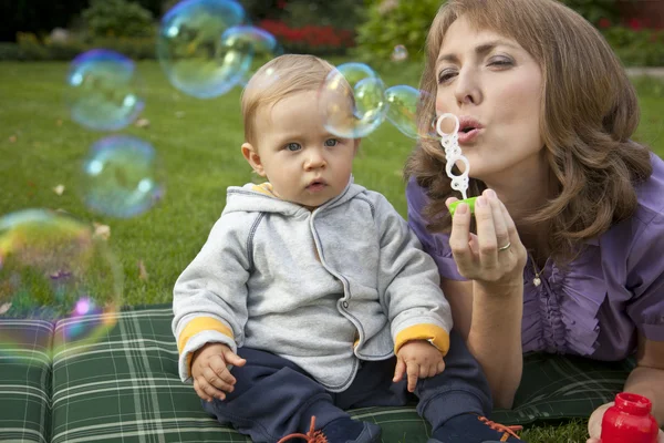 Mère et bébé jouant des bulles dans le jardin — Photo