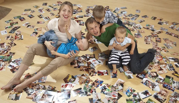 Familie vergnügt sich auf dem Fußboden und sieht Fotos — Stockfoto