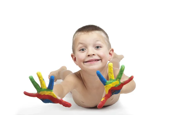 Smiling child laying down with painted hands — Stock Photo, Image