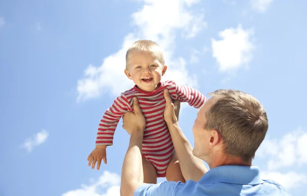 Vater wirft Baby auf Himmelshintergrund — Stockfoto