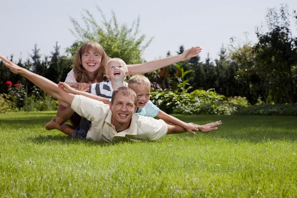 Família feliz jogando um avião no jardim Imagem De Stock
