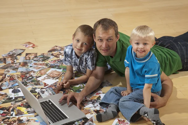 Familjen tittar på laptop på golvet Royaltyfria Stockfoton