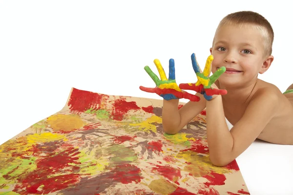 Niño sonriente con manos pintadas y papel de arte —  Fotos de Stock