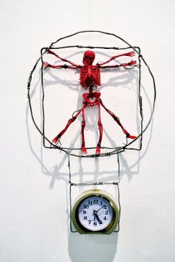 Red toy skeleton, which hangs over a mechanical alarm clock - a clipart