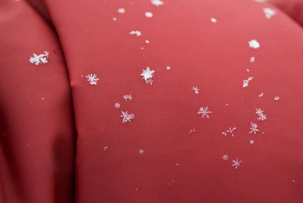 Sneeuwvlok op rode stof — Stockfoto